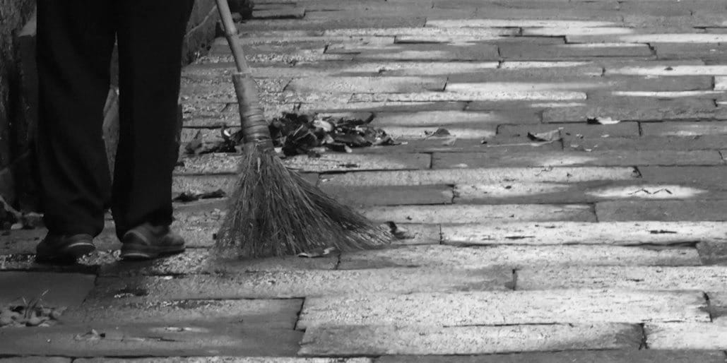 A person with a broom is sweeping the street